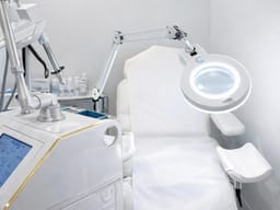 Salle de traitement du cabinet : laser fractionné, fauteuil d'examen et lampe loupe